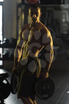 Muscular Man Exercising Abdominal Muscles With Weights In A Modern Fitness Club