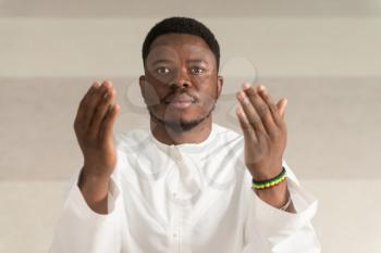 African Muslim Man Making Traditional Prayer To God While Wearing A Traditional Cap Dishdasha