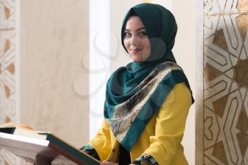 Muslim Woman Making Traditional Prayer To God While Reading The Quran In Mosque