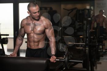 Muscular Man Doing Heavy Weight Exercise For Biceps With Barbell In Gym