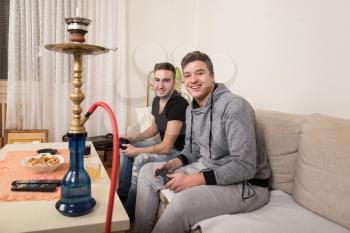 Two Young Brothers Having Happy Time Together Playing Video Games At Home