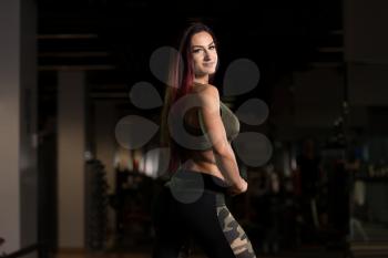 Attractive Young Woman Standing Strong In The Gym And Flexing Muscles - Beautiful Athletic Fitness Model Posing After Exercises