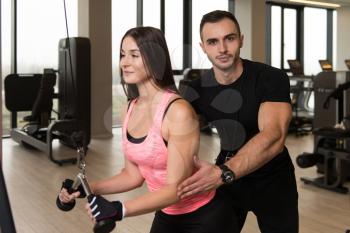 Personal Trainer Showing Young Woman How To Train Triceps In The Gym