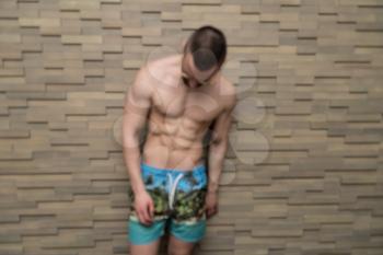 Healthy Young Man Standing Strong Standing Against a Wall and Flexing Muscles - Muscular Athletic Bodybuilder Fitness Model Posing After Exercises - a Place for Your Text