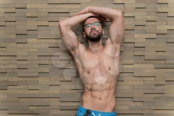 Healthy Young Man Standing Strong Standing Against a Wall and Flexing Muscles - Muscular Athletic Bodybuilder Fitness Model Posing After Exercises - a Place for Your Text
