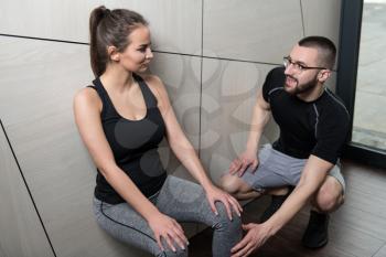 Personal Trainer Showing Young Woman How To Train Legs Leaning on the Wall