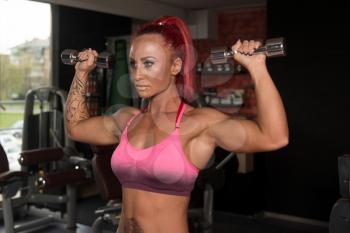 Fitness Woman Working Out Shoulders In Fitness Center - Dumbbell Concentration Curls