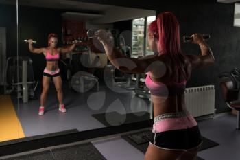 Fitness Woman Working Out Shoulders In Fitness Center - Dumbbell Concentration Curls