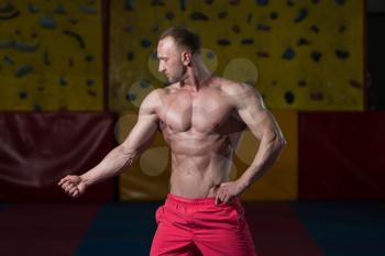 Healthy Young Man Standing Strong In The Gym And Flexing Muscles - Muscular Athletic Bodybuilder Fitness Model Posing After Exercises