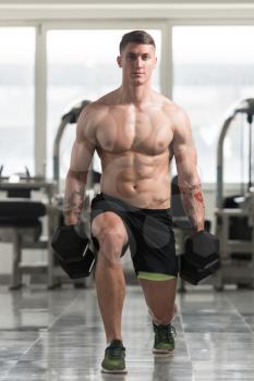 Healthy Fitness Man Working Out Legs With Dumbbells In A Gym - Front Squat Exercise