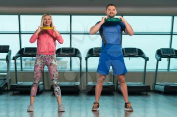 Young Woman And Men Doing Exercise With Weights In The Gym