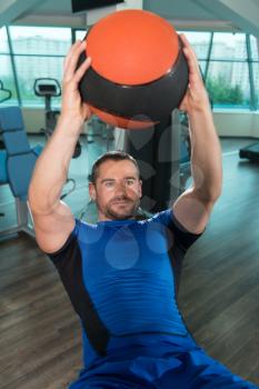 Young Fitness Man Working Out Abs With Fitness Ball On Adjustable Bench In Gym Center