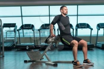Young Fitness Man Working Out Triceps On Roman Chair In Fitness Center