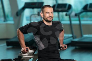 Young Fitness Man Working Out Triceps On Roman Chair In Fitness Center