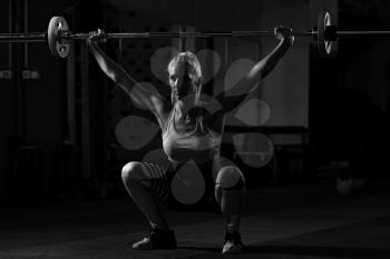 Fitness Woman Performing Barbell Squats - One Of The Best Bodybuilding Exercise For Legs