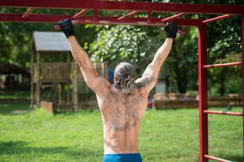 Muscular Built Athlete Working Out In An Outdoor Gym - Doing Chin-Ups