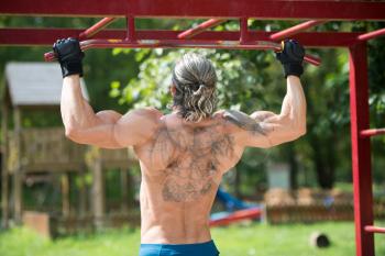 Muscular Built Athlete Working Out In An Outdoor Gym - Doing Chin-Ups
