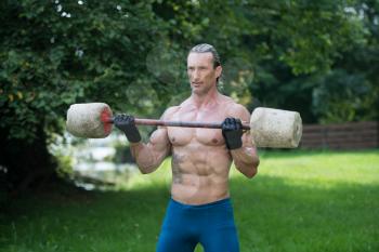Muscular Adult Man Doing A Exercise For Biceps With Made Hand Barbell Outdoors Workout