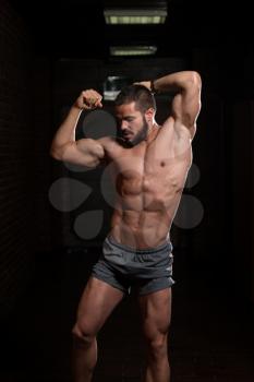 Healthy Young Model Standing Strong in the Fitness Center and Flexing Muscles - Muscular Athletic Bodybuilder Man Posing After Exercises