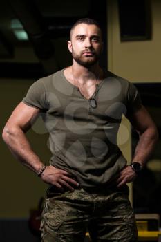 Portrait Of A Young Physically Fit Man Showing His Well Trained Body In Green Shirt and Army Pants - Muscular Athletic Bodybuilder Fitness Model Posing After Exercises