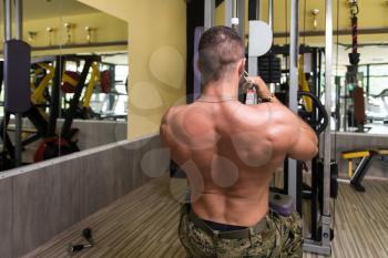 Handsome Bodybuilder Doing Heavy Weight Exercise For Back On Machine In Army Pants