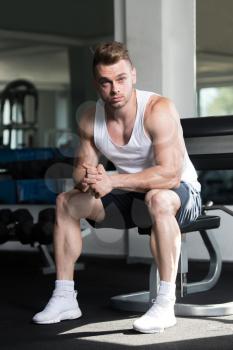 Attractive Man Resting On Bench After Exercise In Fitness Center