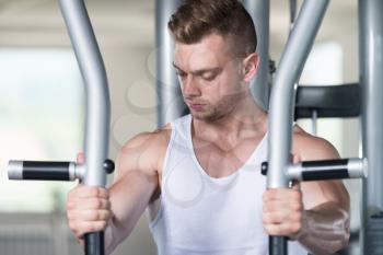 Handsome Muscular Fitness Bodybuilder Doing Heavy Weight Exercise For Chest On Machine With Cable In The Gym