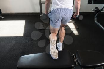 Athlete Working Out Hamstrings In A Gym With Dumbbells