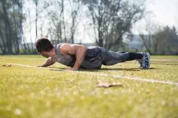 Attractive Man Doing Push Up in City Park Area - Training and Exercising for Endurance - Fitness Healthy Lifestyle Concept Outdoor