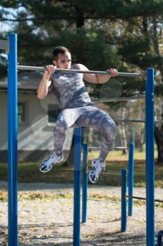 Young Man Doing Crossfit Exercise With Dips Bar in City Park Area - Training and Exercising for Endurance - Healthy Lifestyle Concept Outdoor