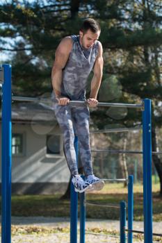 Attractive Man Doing Crossfit Exercise With Dips Bar in City Park Area - Training and Exercising for Endurance - Healthy Lifestyle Concept Outdoor