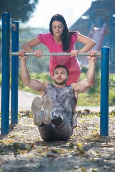 Attractive Couple Doing Crossfit Exercise With Dips Bar in City Park Area - Training and Exercising for Endurance - Healthy Lifestyle Concept Outdoor
