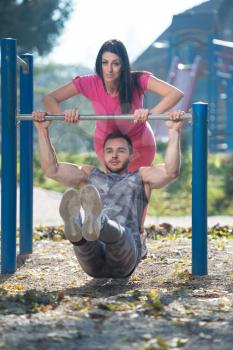 Young Couple Doing Crossfit Exercise With Dips Bar in City Park Area - Training and Exercising for Endurance - Healthy Lifestyle Concept Outdoor