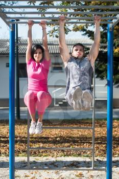 Young Couple Doing Crossfit Exercise With Dips Bar in City Park Area - Training and Exercising for Endurance - Healthy Lifestyle Concept Outdoor