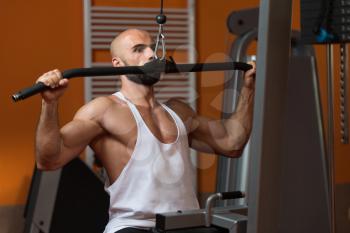 Handsome Athlete Doing Heavy Weight Exercise For Back On Machine In Gym