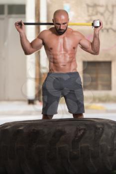 Athletic Man Resting - Workout At Gym With Hammer And Tractor Tire