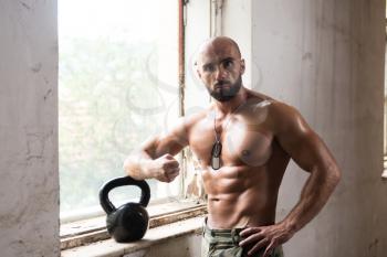 Man Working Out With Kettle Bell In Shelter - Bodybuilder Doing Heavy Weight Exercise With Kettle-bell
