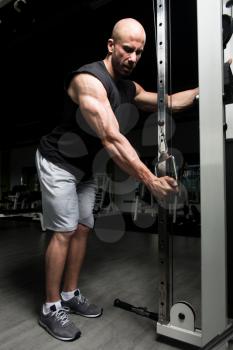 Young Muscular Fitness Bodybuilder Doing Heavy Weight Exercise For Triceps On Machine In The Gym