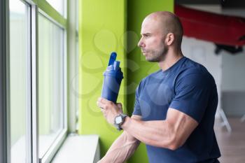 Muscular Man Resting After Exercise And Drinking From Shaker