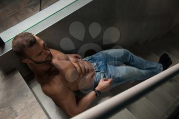 Portrait of a Young Physically Fit Man Showing His Well Trained Body On Stairs - Muscular Athletic Bodybuilder Fitness Model Posing After Exercises on Wall Near the Wall - a Place for Your Text