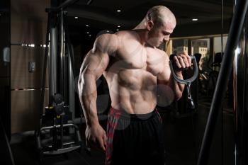 Man In The Gym Exercising On His Biceps On Machine With Cable In The Gym