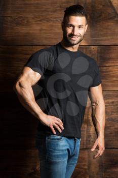 Portrait of a Young Physically Fit Man Showing His Well Trained Body While Wearing Blue Jeans - Muscular Athletic Bodybuilder Fitness Model Posing After Exercises on Wooden Wall - a Place for Your Text