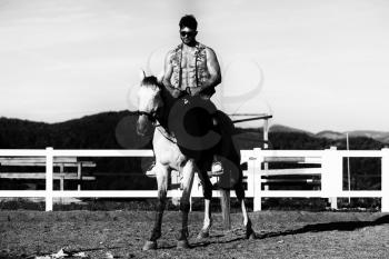 Handsome Macho Man Cowboy Riding on a Horse - Background of Sky and Mountains