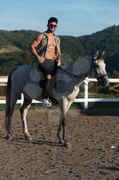 Handsome Macho Man Cowboy Riding on a Horse - Background of Sky and Mountains