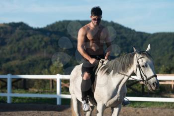 Handsome Macho Man Cowboy Riding on a Horse - Background of Sky and Mountains