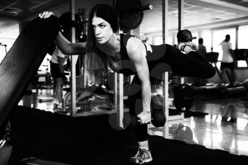 Muscular Fitness Woman Athlete Doing Heavy Weight Exercise For Back and Legs With Dumbbells In The Gym