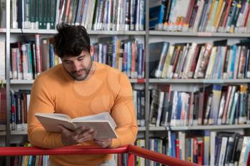 In the Library - Handsome Male Student With Books Working in a High School - University Library - Shallow Depth of Field