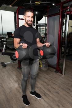 Man Working Out Biceps In A Gym With Medicine Balls