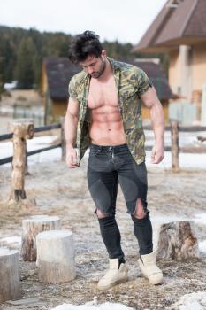 Healthy Young Man Standing Strong Flexing Muscles While Wearing Black Jeans - Muscular Athletic Bodybuilder Fitness Model Posing Outdoors - a Place for Your Text