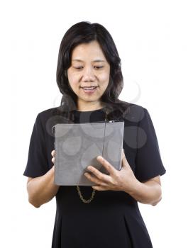 A vertical portrait photo of a mature Asian woman wearing a dark dress while checking her daily email isolated on white